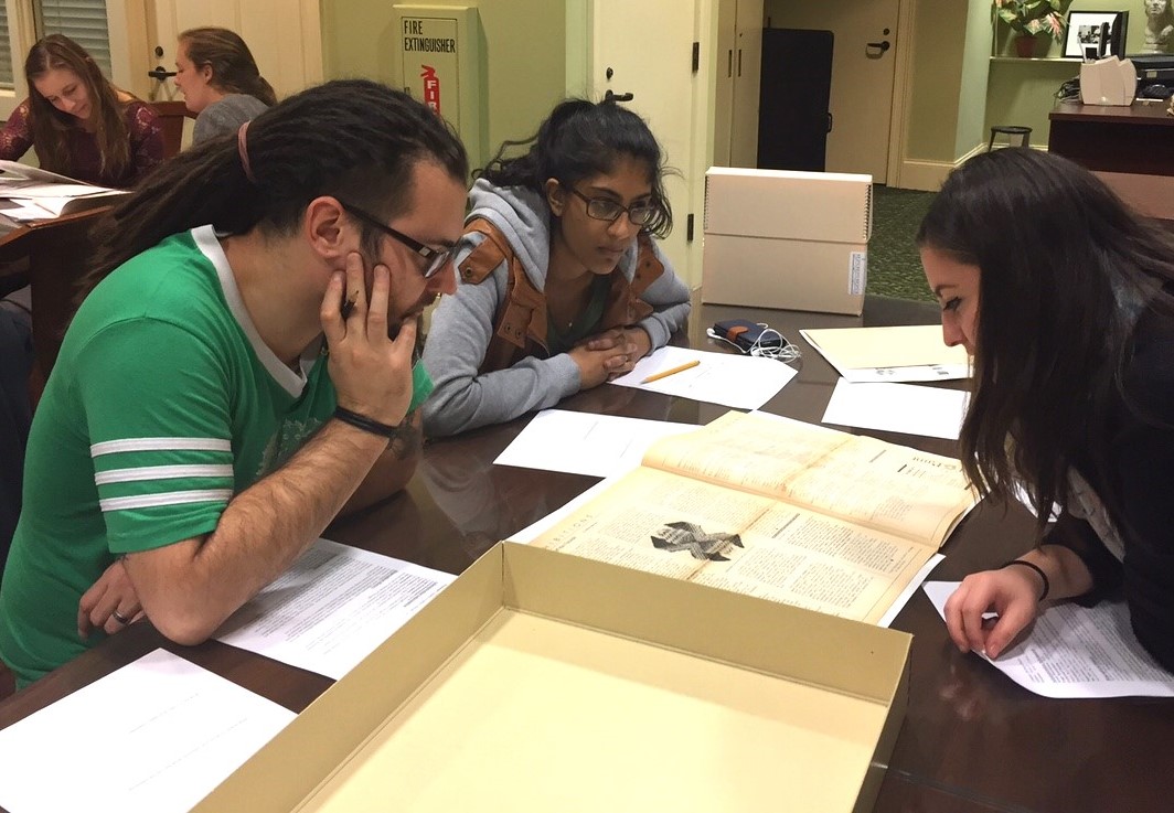 Three students looking at archival materials in the WLA reading room